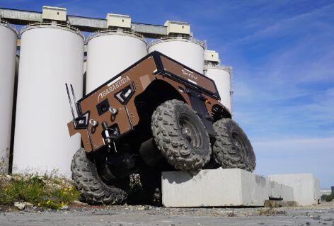 The Barakuda is in motion, navigating over a concrete block, with the imposing silos of La Rochelle port in the backdrop.