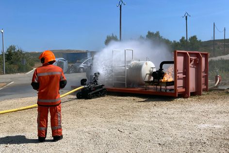 Firefighter operates Rhyno Protect to reduce temperature of a gas reserve, preventing potential explosion risks.