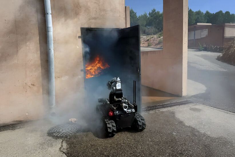 Back view of the Rhyno Protect firefighting robot entering a smoke-filled building through the main entrance during a firefighter training exercise. The robot demonstrates its capability to handle high-risk fire environments, supporting first responders in critical conditions.