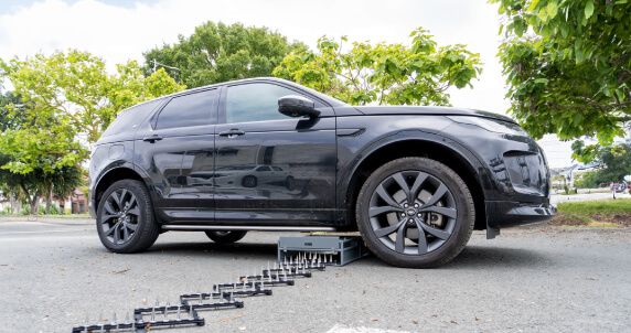 Shark Spike hidden under a large SUV, ready for deployment in a parking lot.